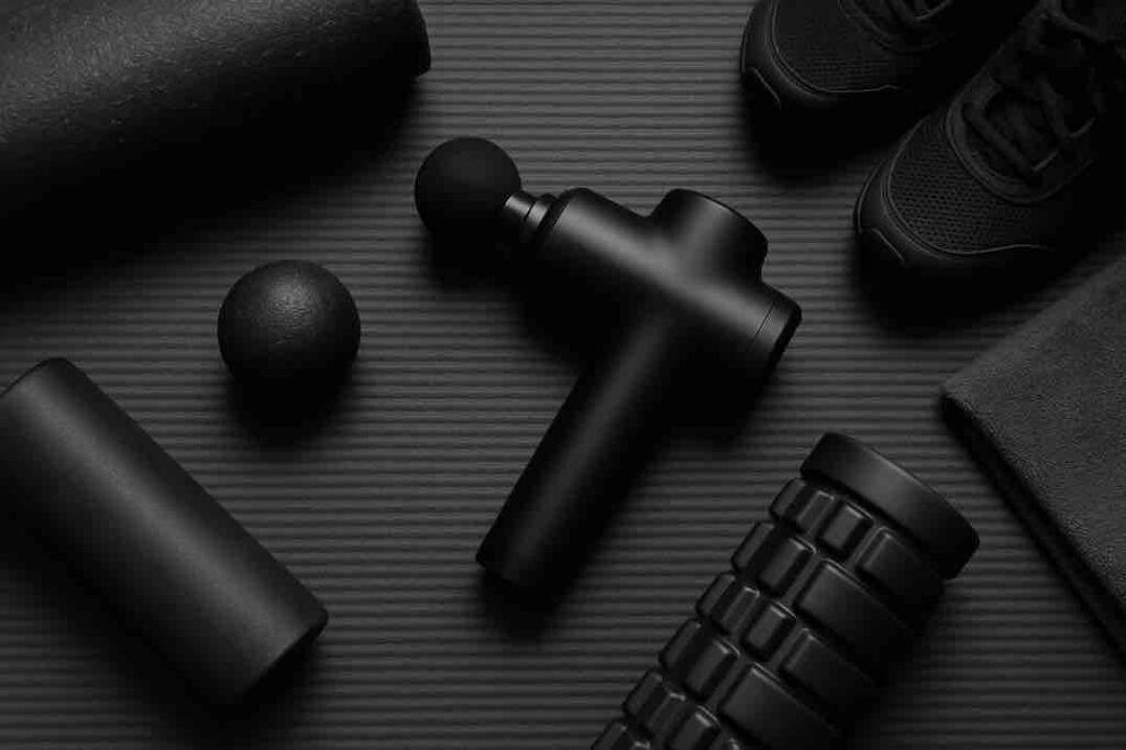 Musta lihashuoltovasara ja palautumisvälineet tummalla joogamatolla.