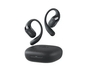 Kuvassa on musta Shokz OpenFit 2 -kuulokesetti, jossa kaksi avointa korvasankakuuloketta leijuu latauskotelon yläpuolella. Kuulokkeissa on kaareva korvasanka ja pienikokoinen kuulokepää, joka lepää korvan ulkopuolella. Latauskotelo on matala ja pyöreäreunainen, ja sen etupuolella näkyy pieni LED-merkkivalo. Tausta on yksivärinen ja korostaa tuotteen sileitä pintoja.